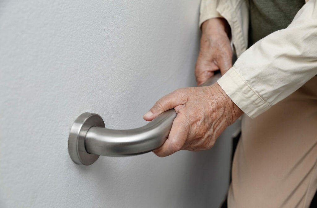 A senior holds onto a grab bar to support their weight and balance while getting up to prevent a serious fall