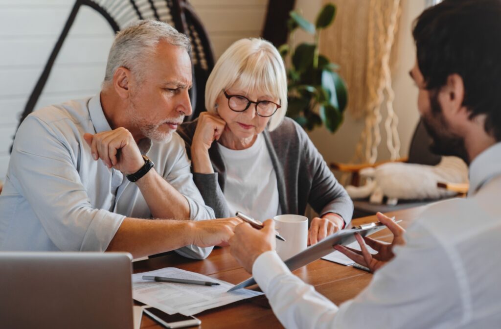 A senior couple show affection while going over the financial assistance offered by assisted living with a staff member