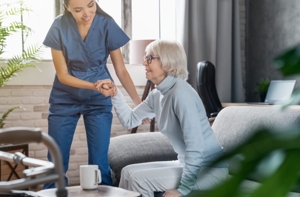 Someone is helped into their chair by a worker at an assisted living community.