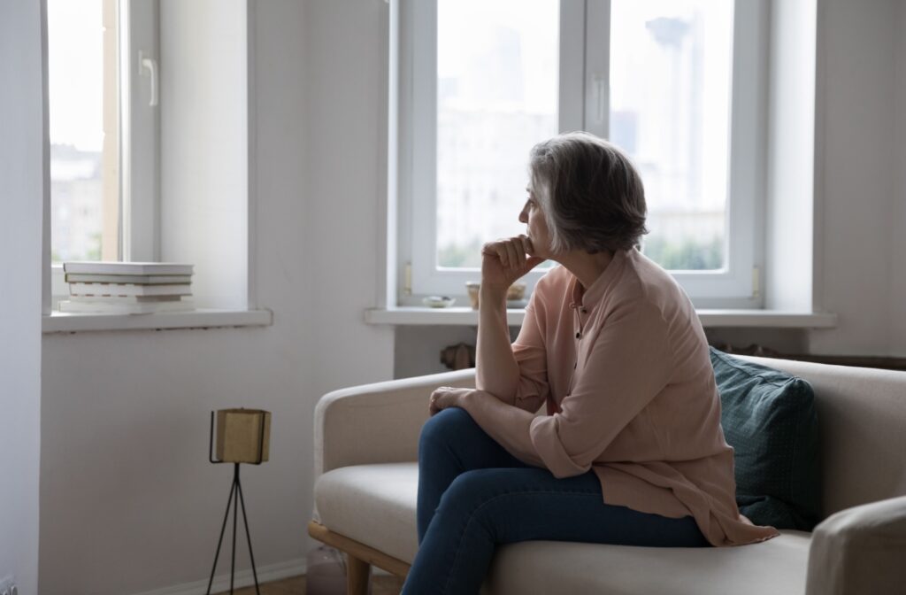A sad and lonely senior looks out their window.
