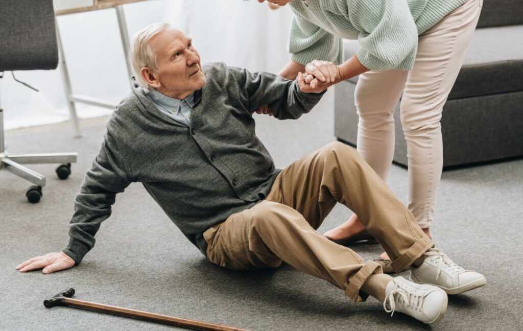 A caregiver helps a senior up after a fall.